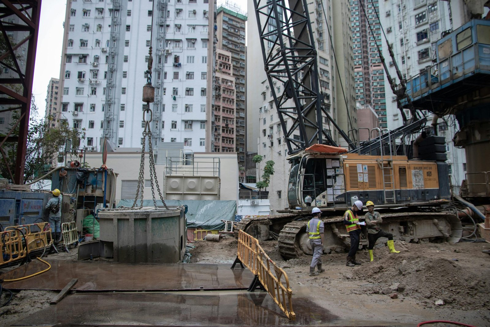 City construction site with workers, cranes, and high-rise buildings.